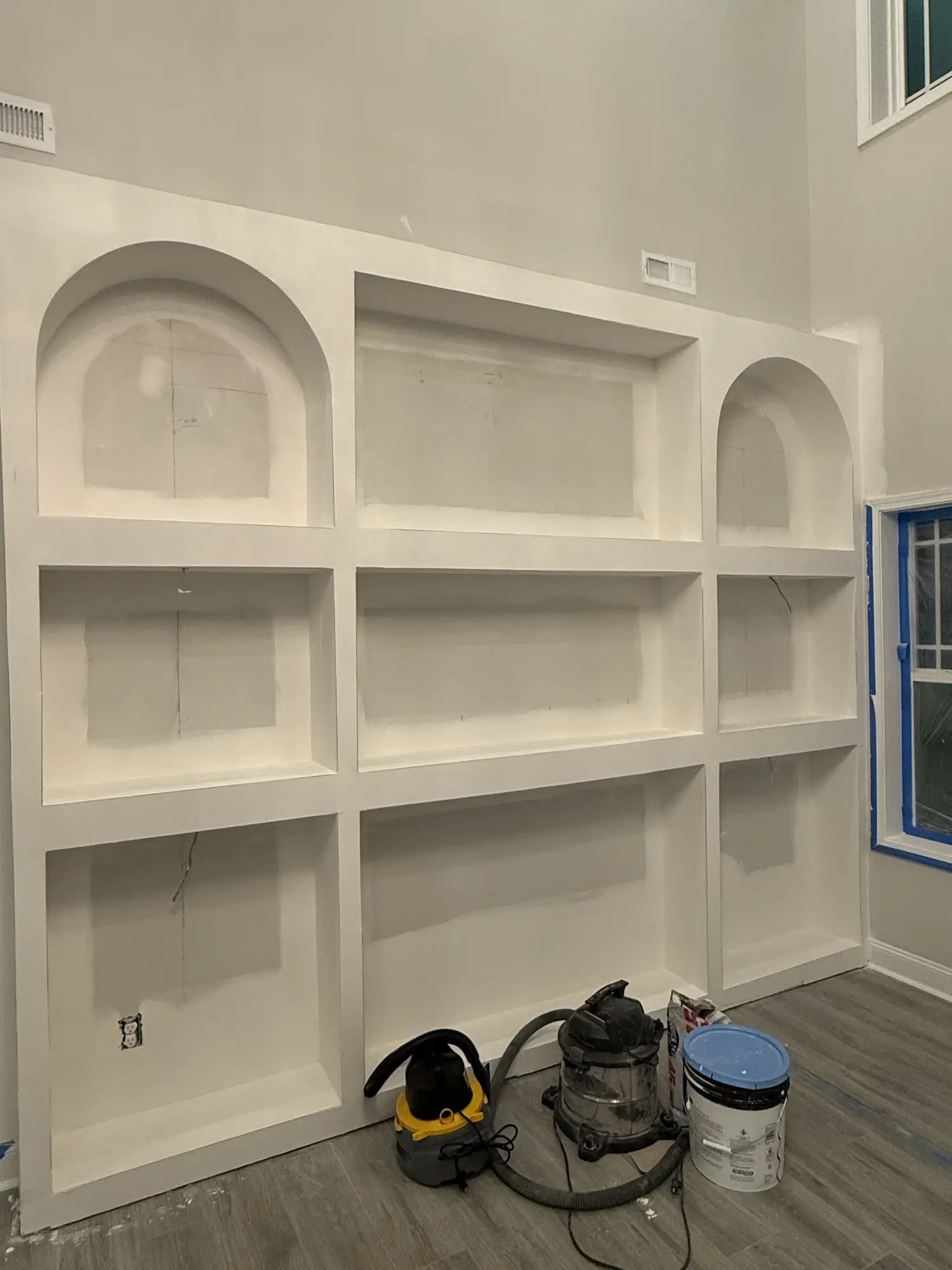 Arched built-in shelving unit in drywall stage before painting