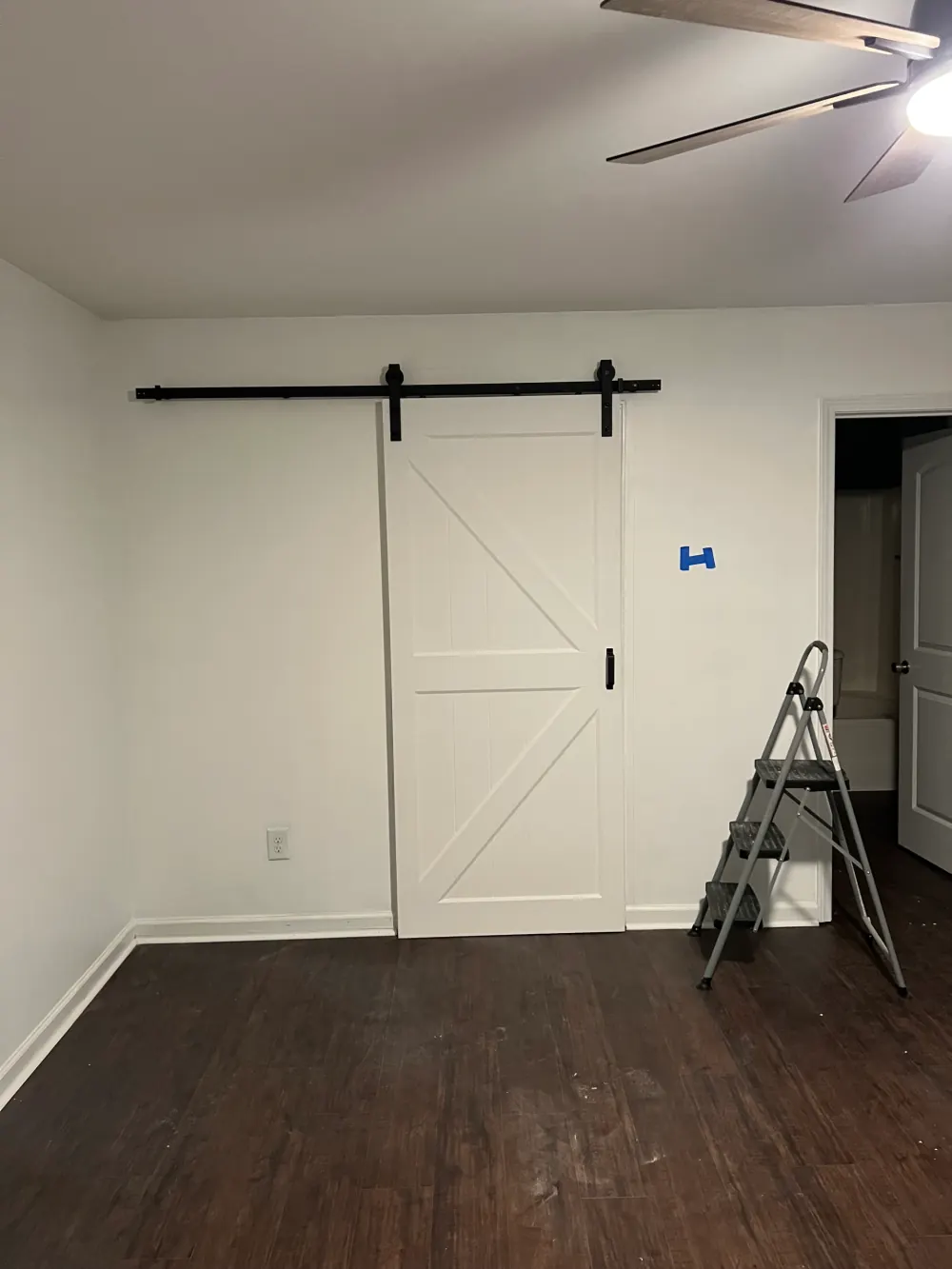 Sliding barn door hung on a black rail in a newly finished room