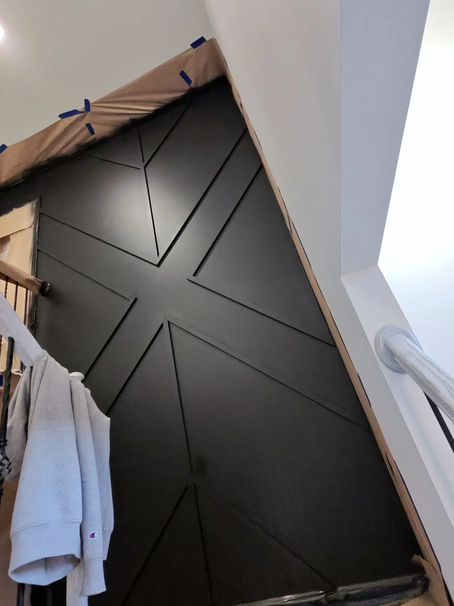 Geometric panel door painted black, masking still on