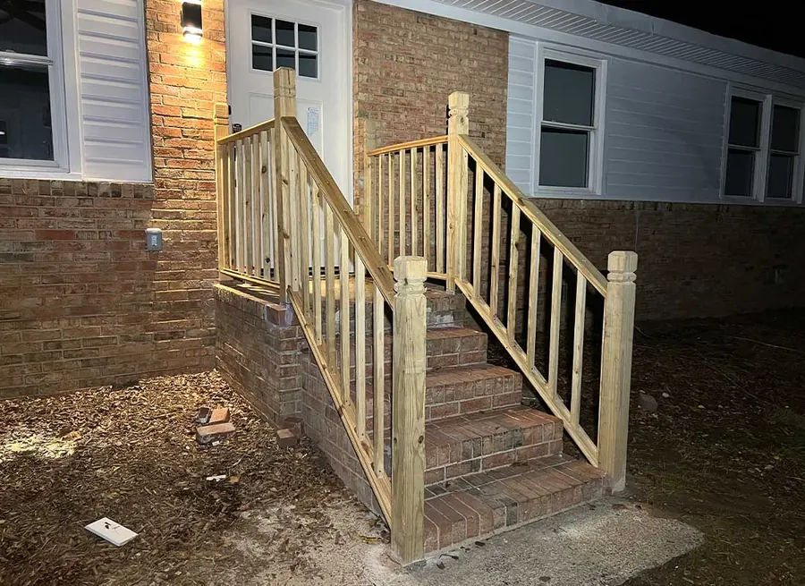 New wooden handrails built on brick front steps, photographed at handover