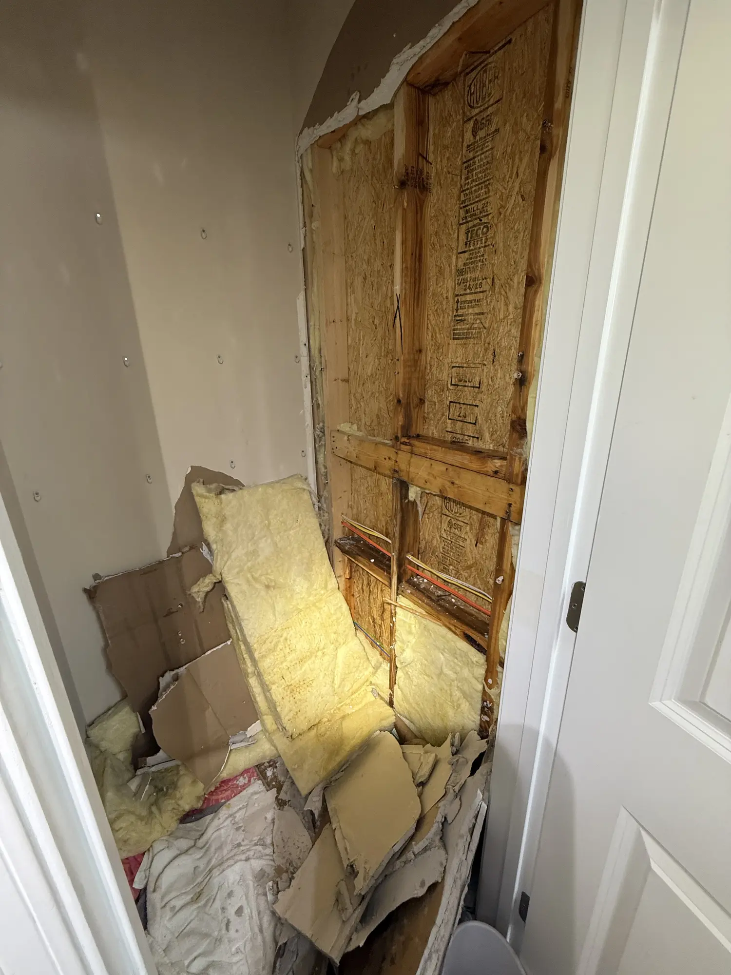Closet wall opened up with insulation exposed during a repair