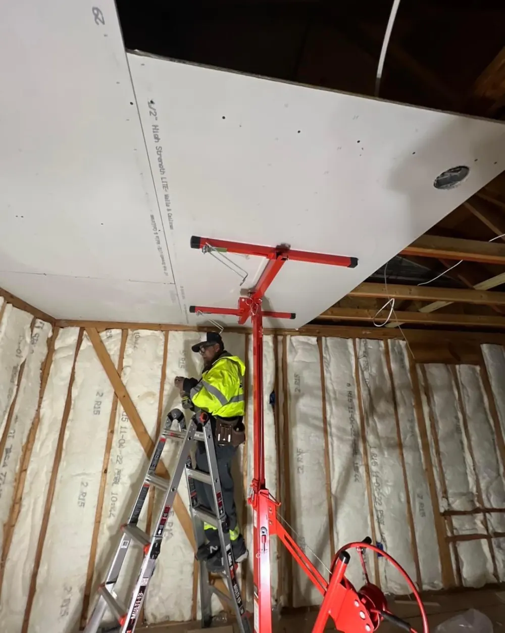 A drywall sheet lifted to a ceiling on a panel lift during an Obsidianwise job