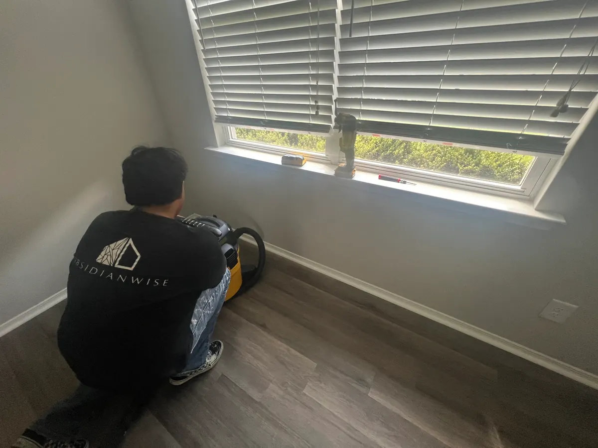 An Obsidianwise team member finishing a repair beside a window in a client's home