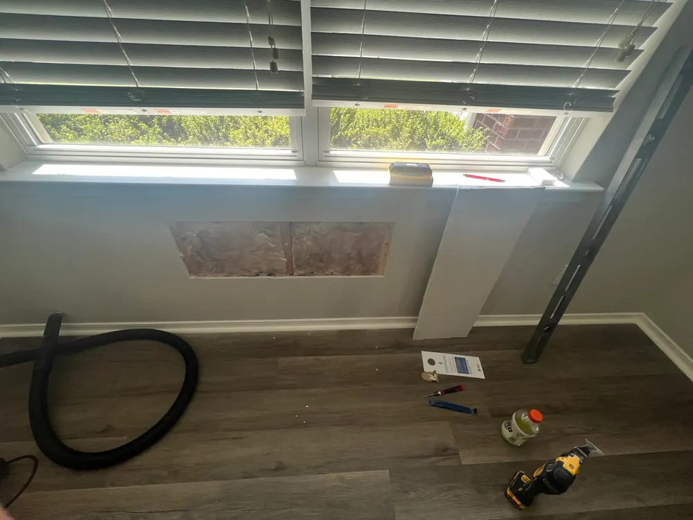 Repaired and skimmed drywall under a window, ready for paint