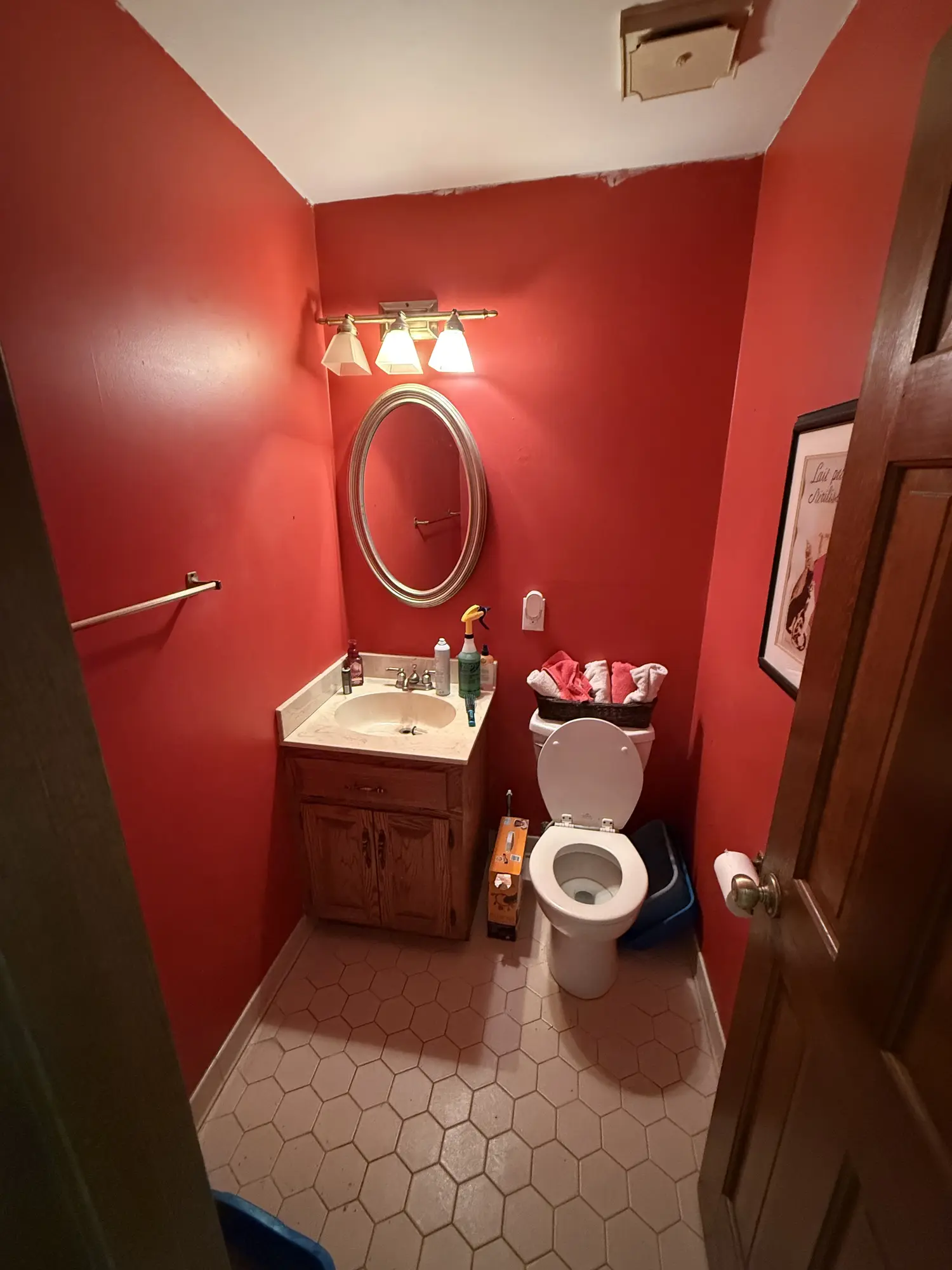 Red painted bathroom with dated fixtures before remodel