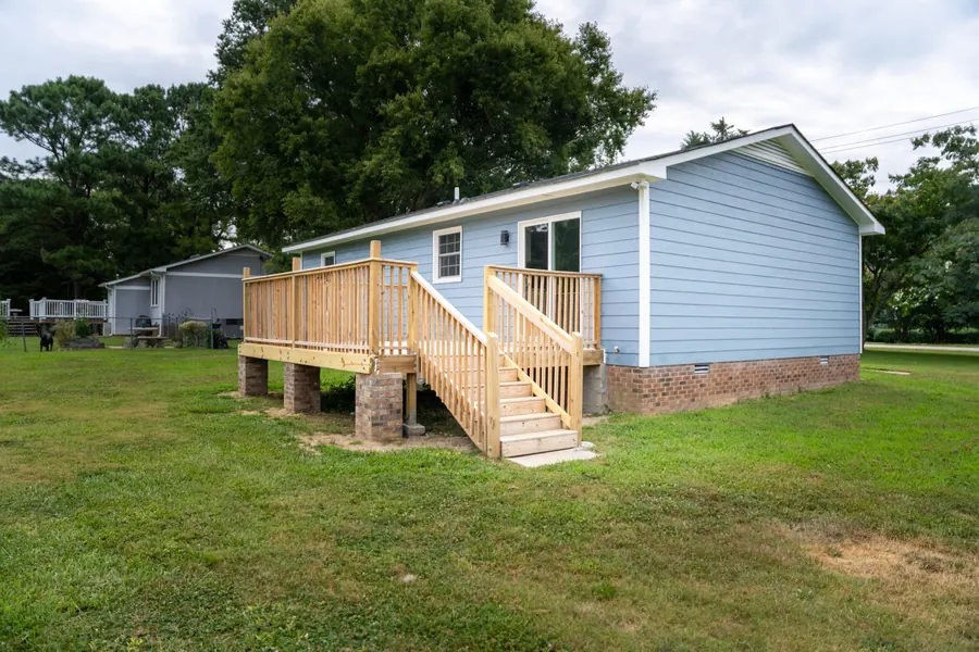 Blue house with a new wooden deck and steps after an exterior remodel by Obsidianwise