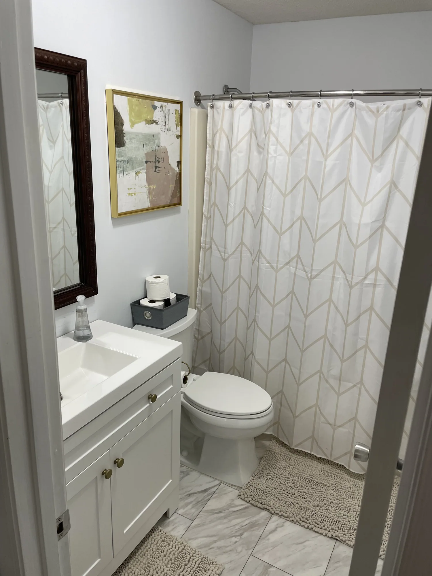 Finished bathroom with a white vanity, marble-look tile floor and hung shower curtain