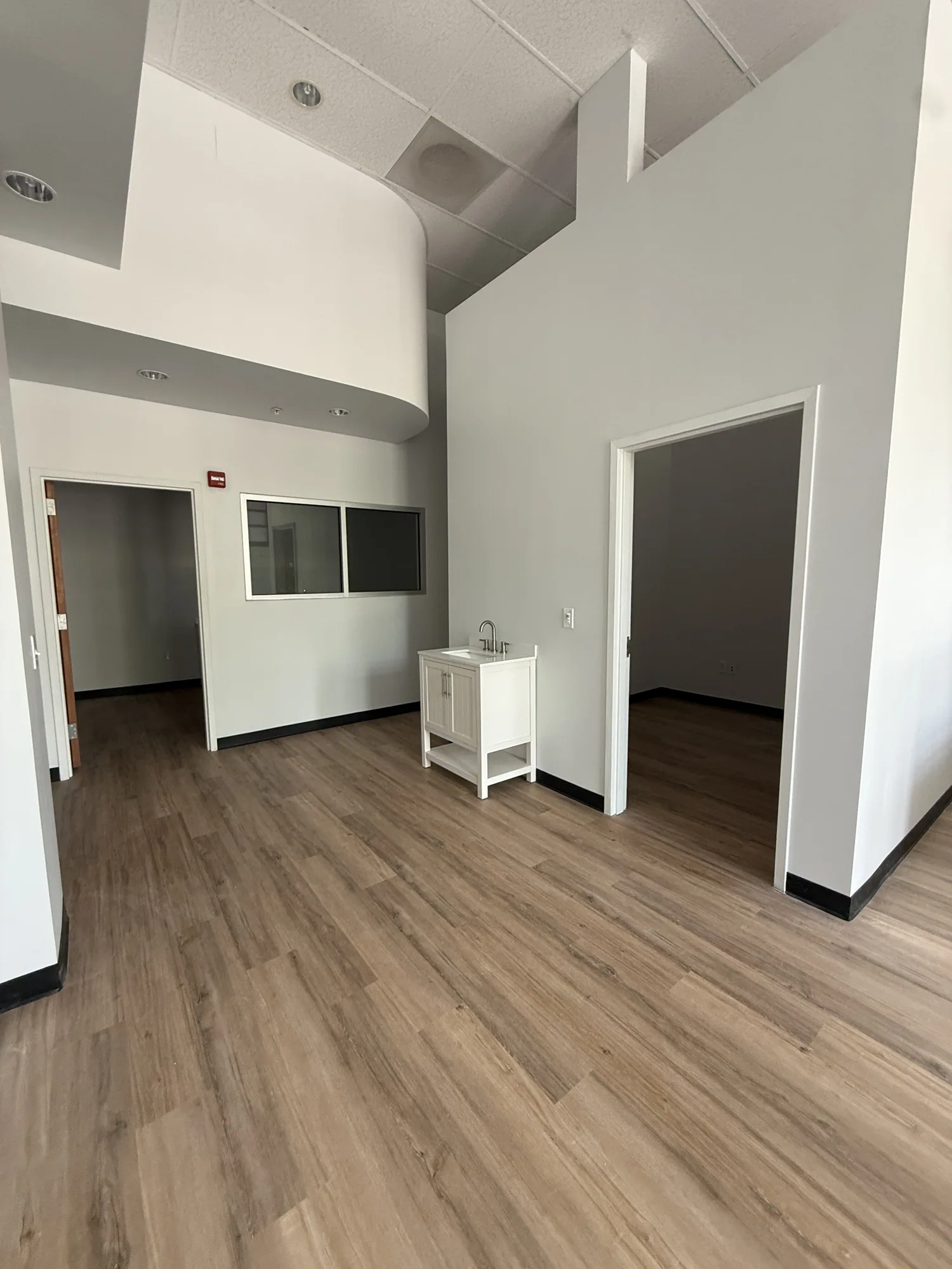 Finished commercial suite with high white walls, an interior window and new wood-look plank flooring