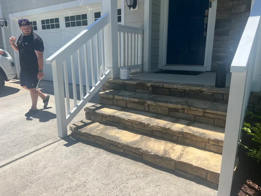 An Obsidianwise team member outside a client's home with freshly painted porch handrails