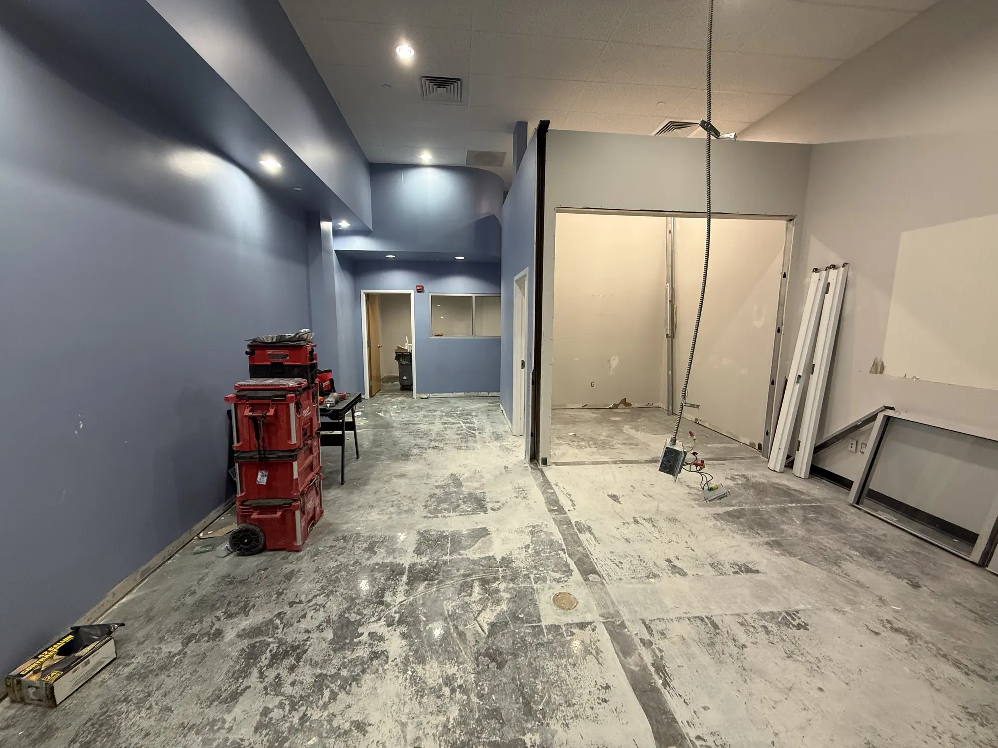 Office interior mid repaint with tools staged on the bare floor