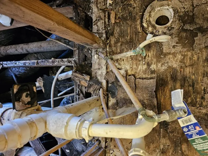 Rotted subfloor opened up around plumbing lines, before repair