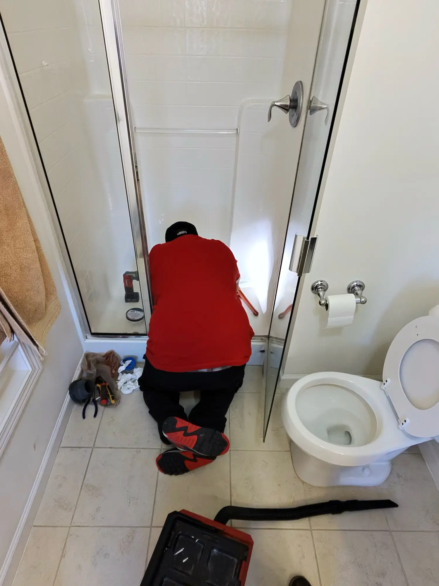 An Obsidianwise team member adjusting a glass shower door during a bathroom job