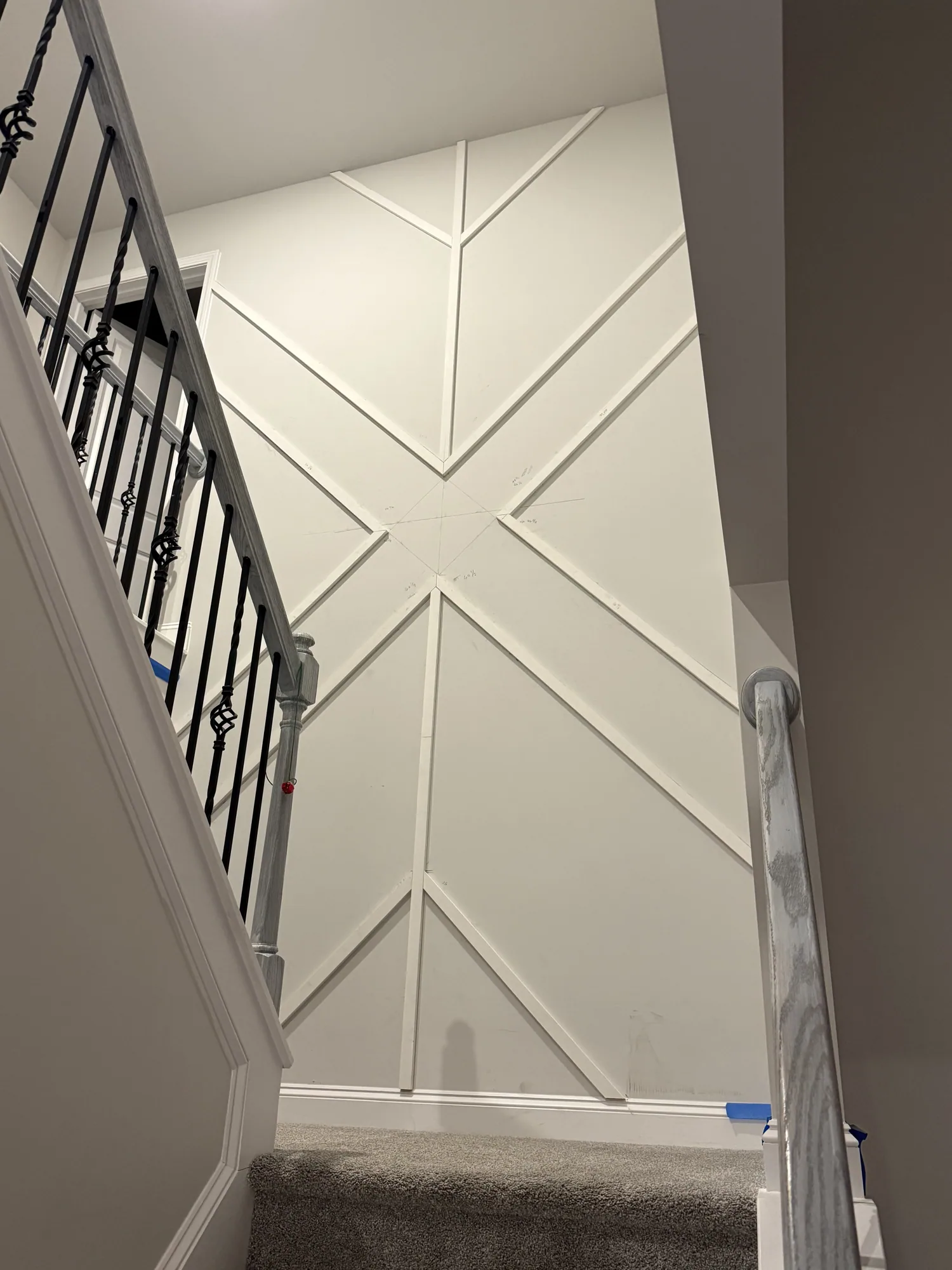 Finished white geometric trim accent wall on a stairwell